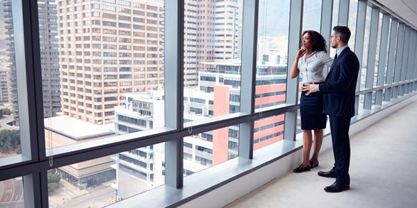 coworkers looking out at city skyline from office building window