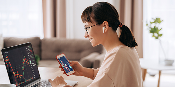 Woman viewing her investments on her phone and laptop